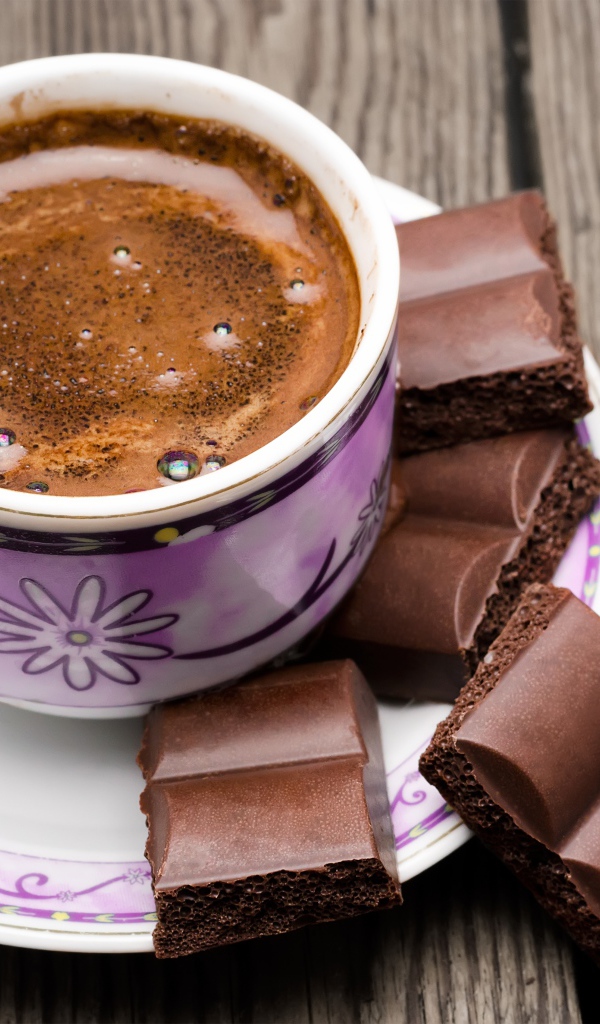 Чашка кофе на столе с кусочками шоколада