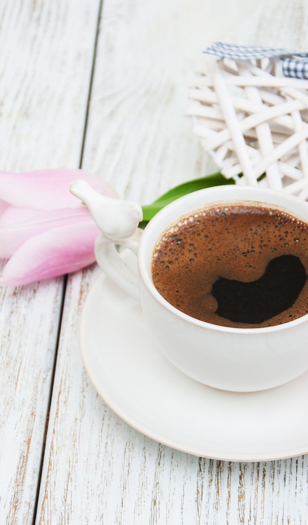 Чашка кофе на столе с розовыми тюльпанами и плетеным сердцем