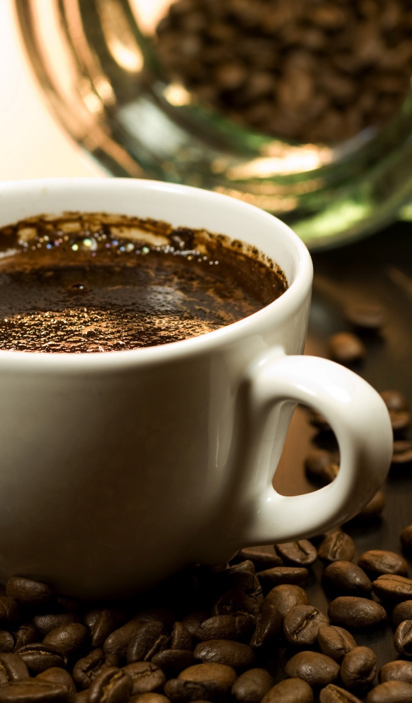 Чашка горячего кофе на столе с зернами
