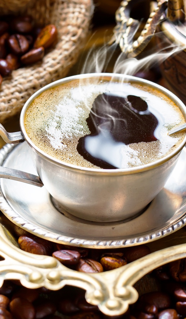 Чашка горячего вкусного кофе на столе с зернами