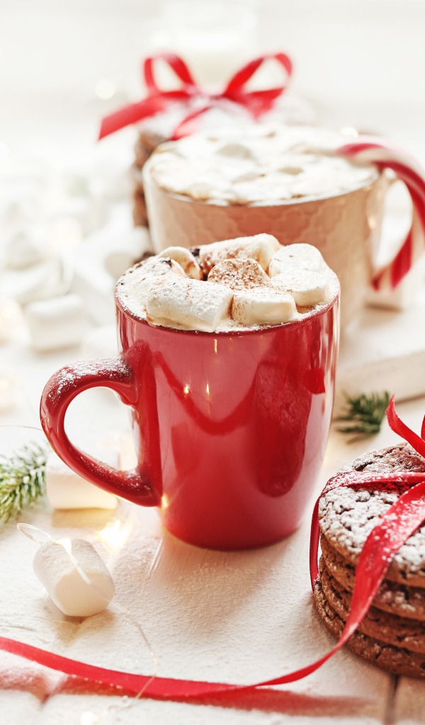 Чашки напитка с маршмеллоу на столе с печеньем