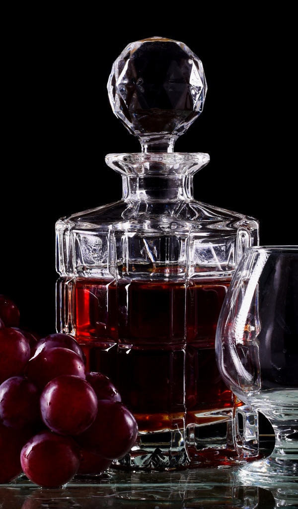 Графин с коньяком на столе с бокалами и виноградом