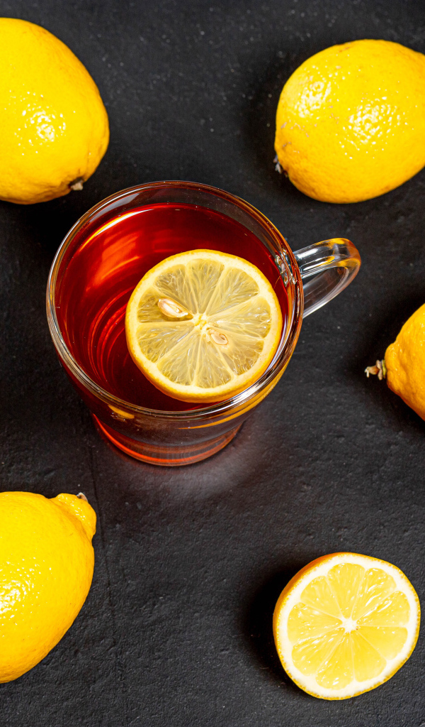 Стеклянная чашка чая с лимоном на сером столе 