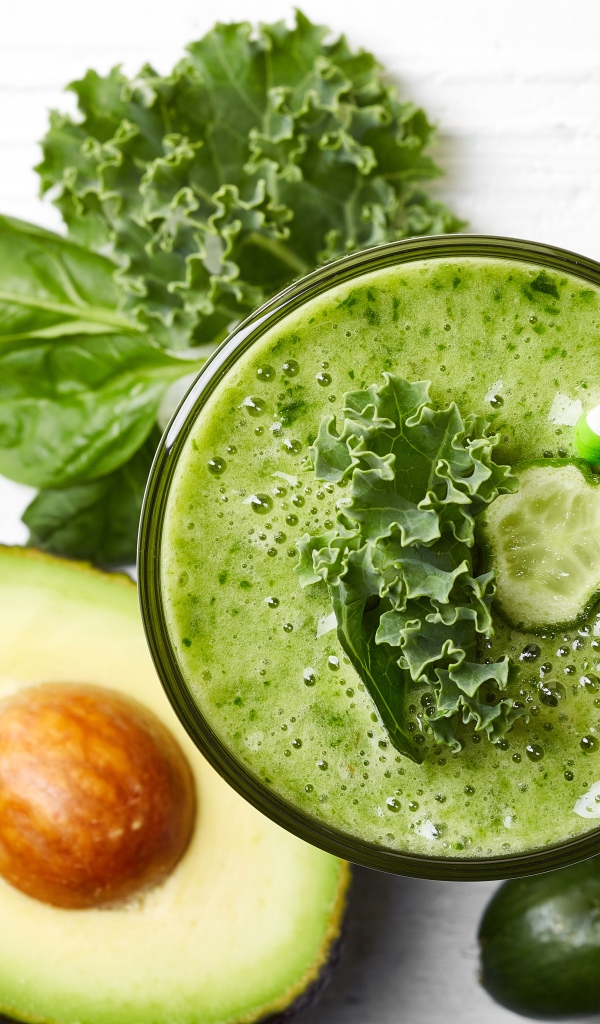 Зеленый смузи на столе с огурцом, авокадо и зеленью