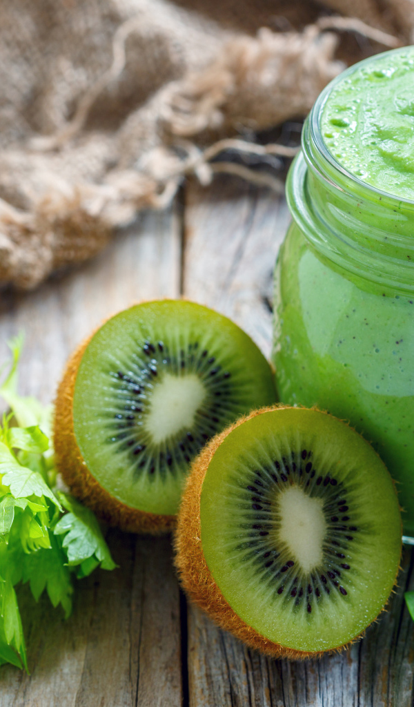 Зеленое смузи на столе с киви и зеленью 