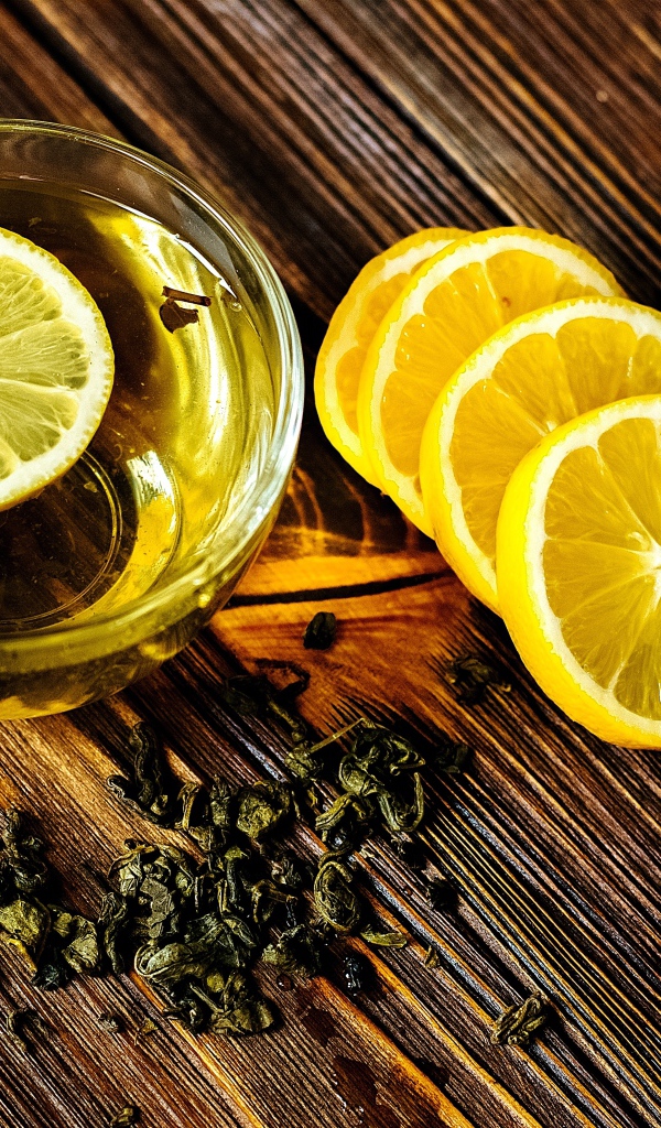 Зеленый чай в стеклянной чашке на столе с лимоном 