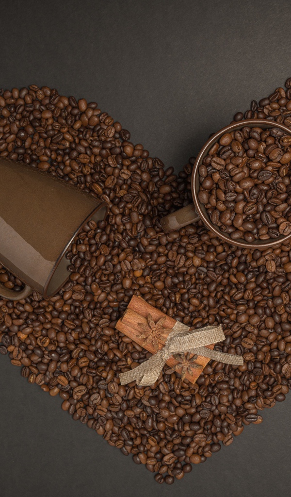 Сердце из кофейных зерен на сером фоне с кружками 