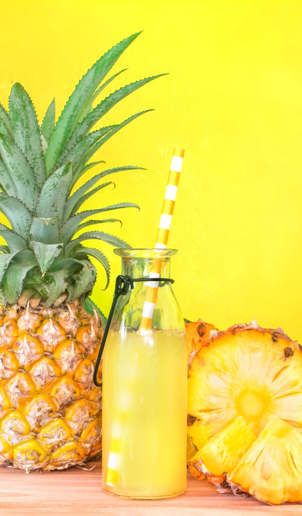 Сок в бутылке на столе с ананасами