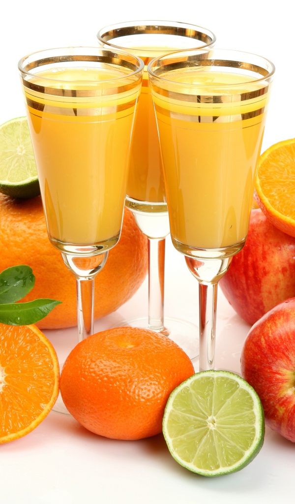 Сок в фужерах на столе с яблоками и мандаринами 