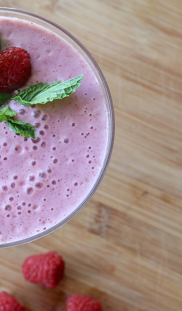 Малиновый смузи в стакане на столе с герберами