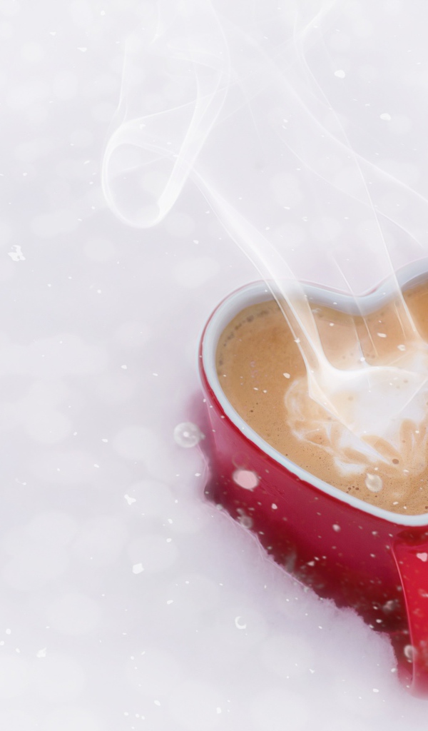 Красная чашка в форме сердца с кофе на снегу