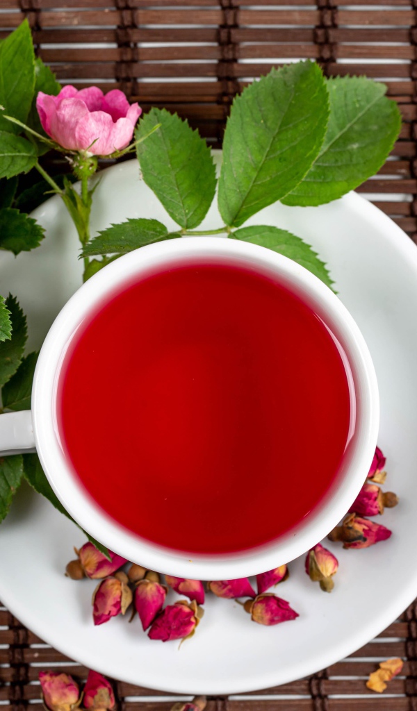 Красный чай с шиповника на столе с цветами
