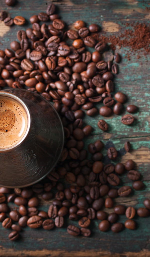 Турка с кофе на столе с зернами и зелеными листьями