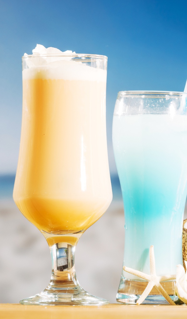 Два коктейля с кокосом на столе на тропическом пляже