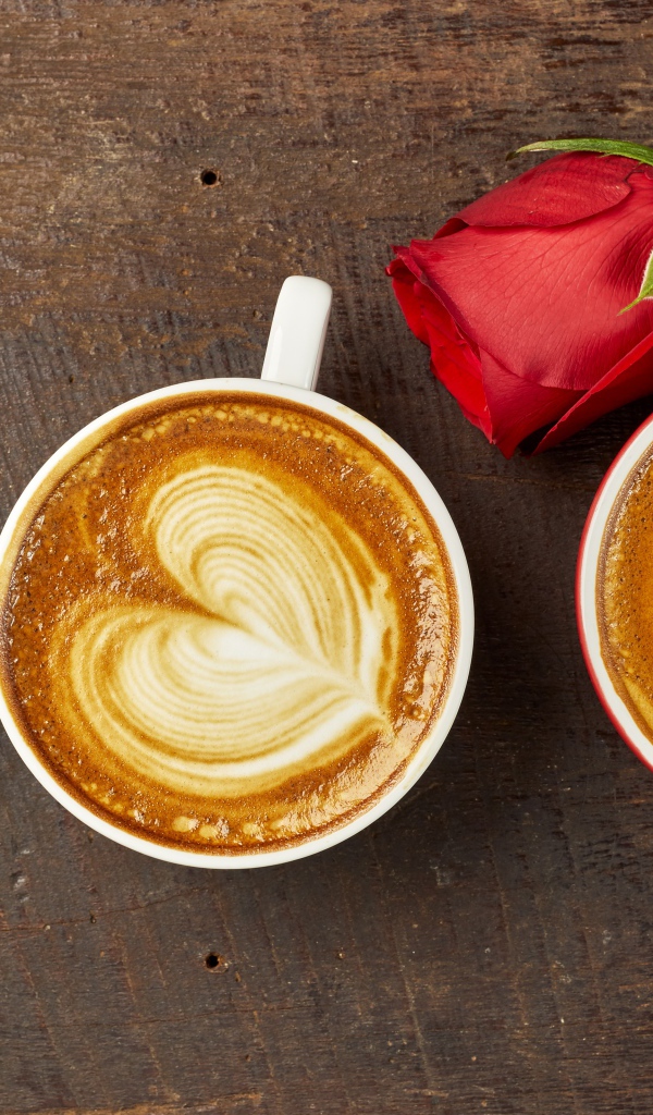 Две чашки капучино на столе с красной розой 