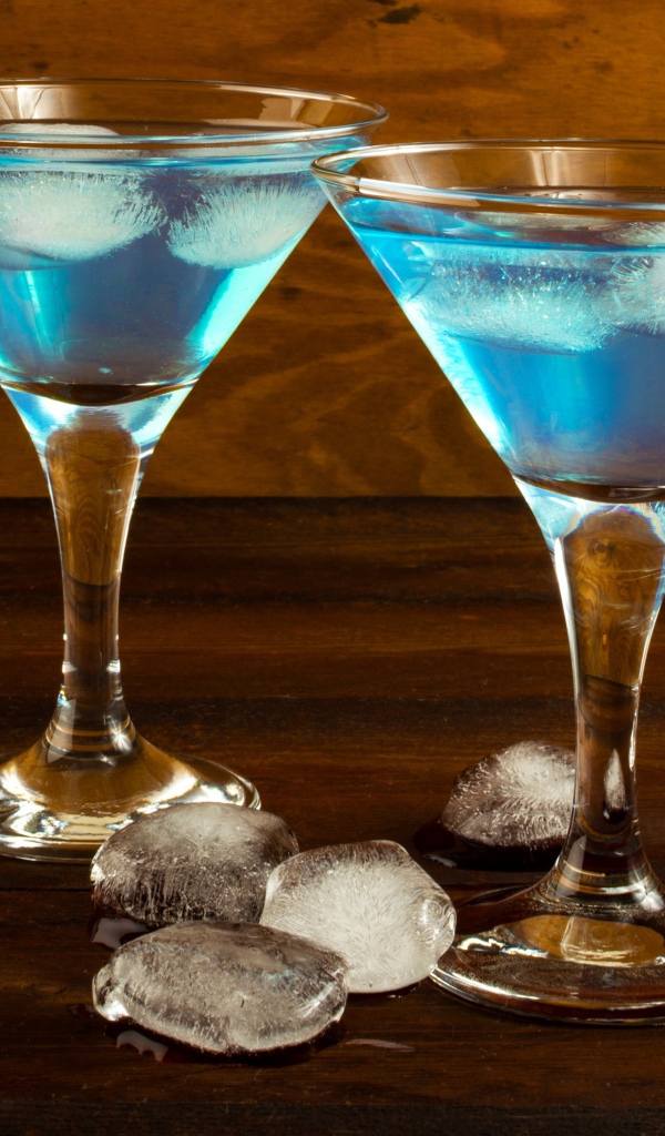 Два бокала коктейля на столе с кусочками льда