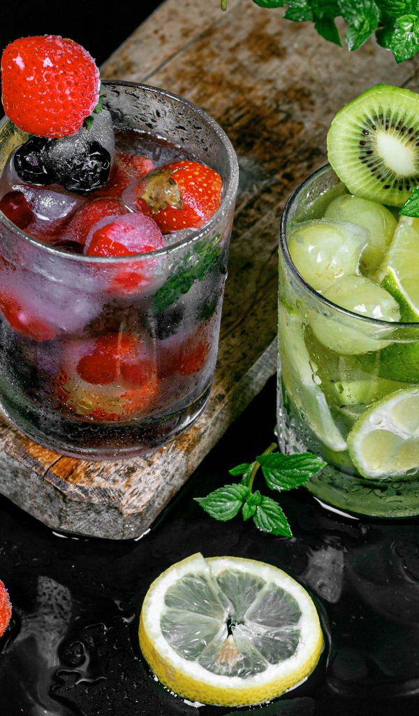 Два стакана мохито на столе с мятой, лимоном и клубникой 