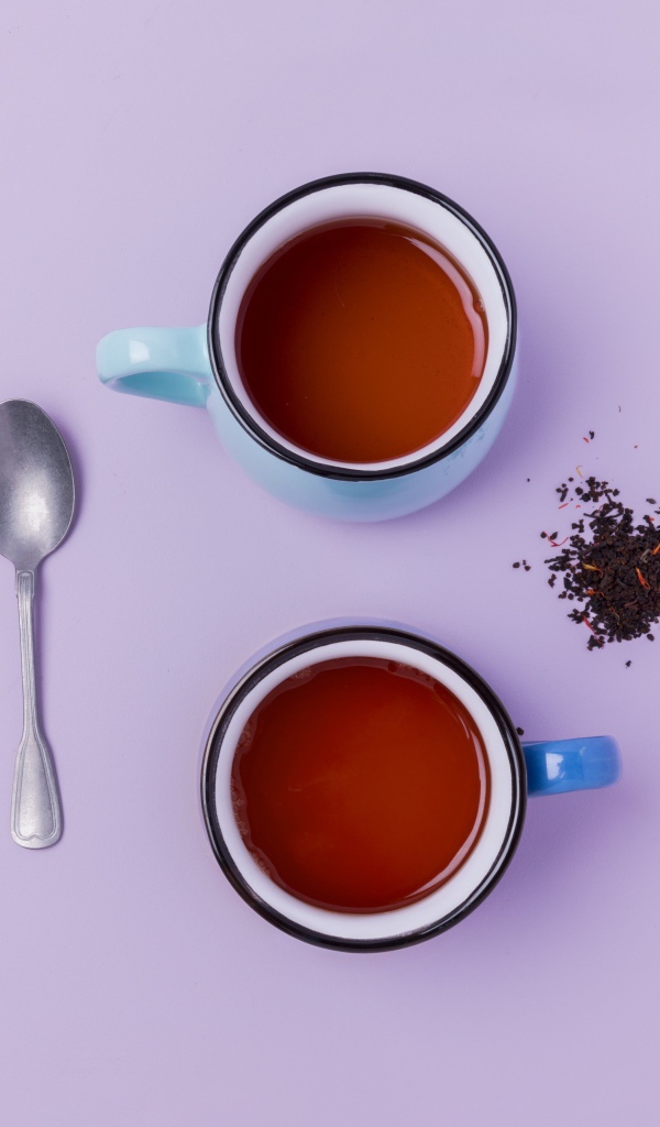 Две железные чашки чая на сиреневом фоне с ложкой