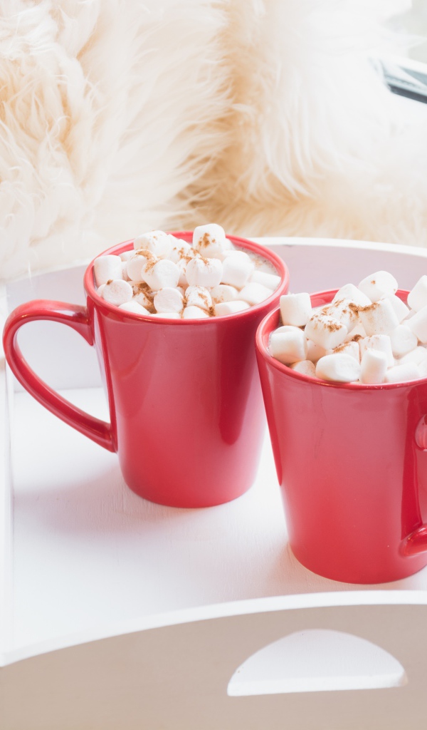 Две красные чашки с маршмеллоу у окна