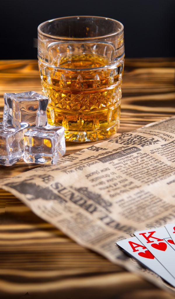 Виски со льдом на столе с картами, газетой и шляпой