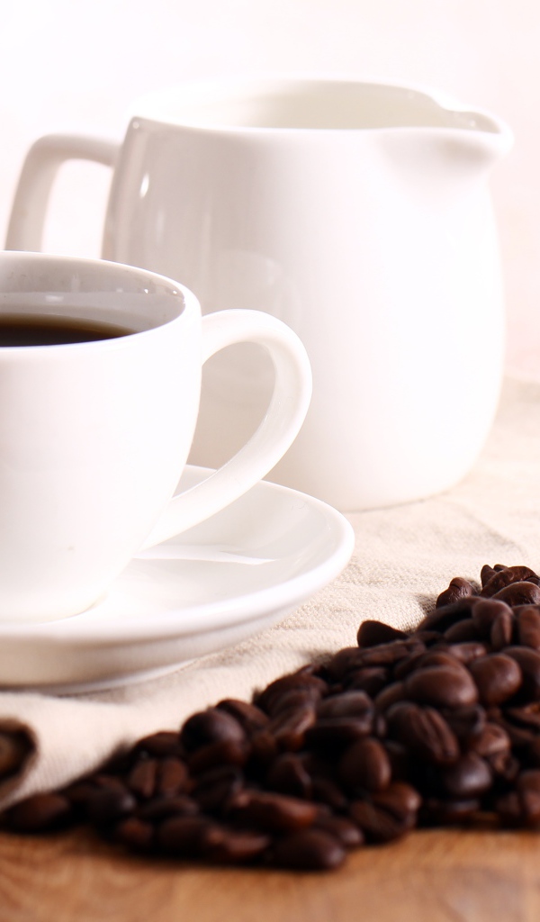 Белая чашка кофе на столе с молоком и зернами