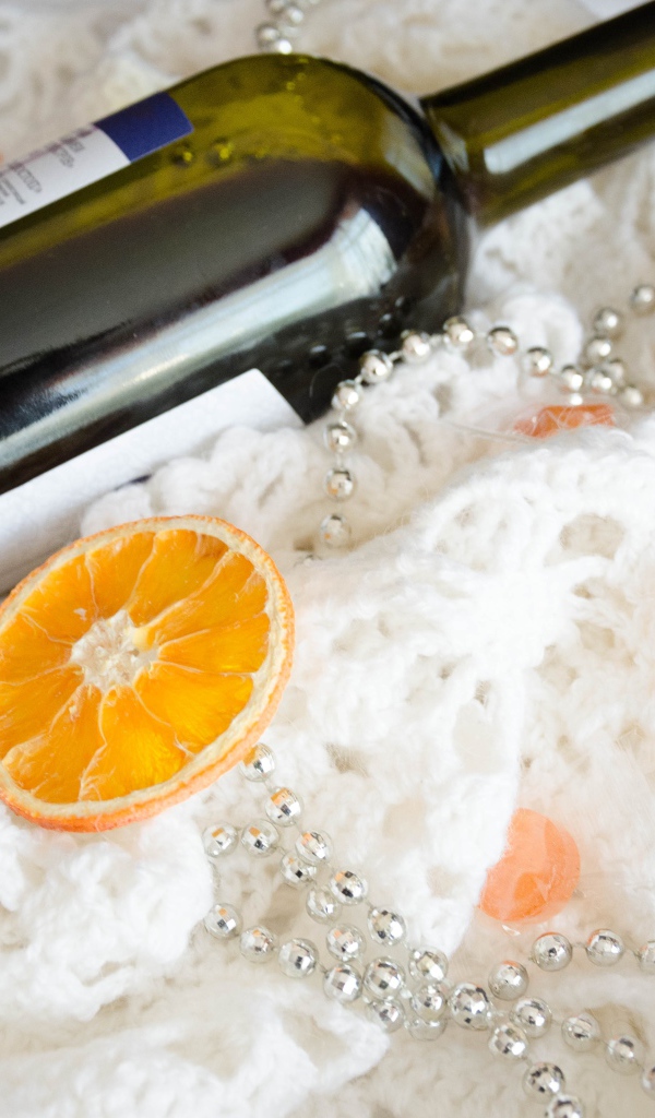 Бутылка вина и кусочки апельсина на белом платке 