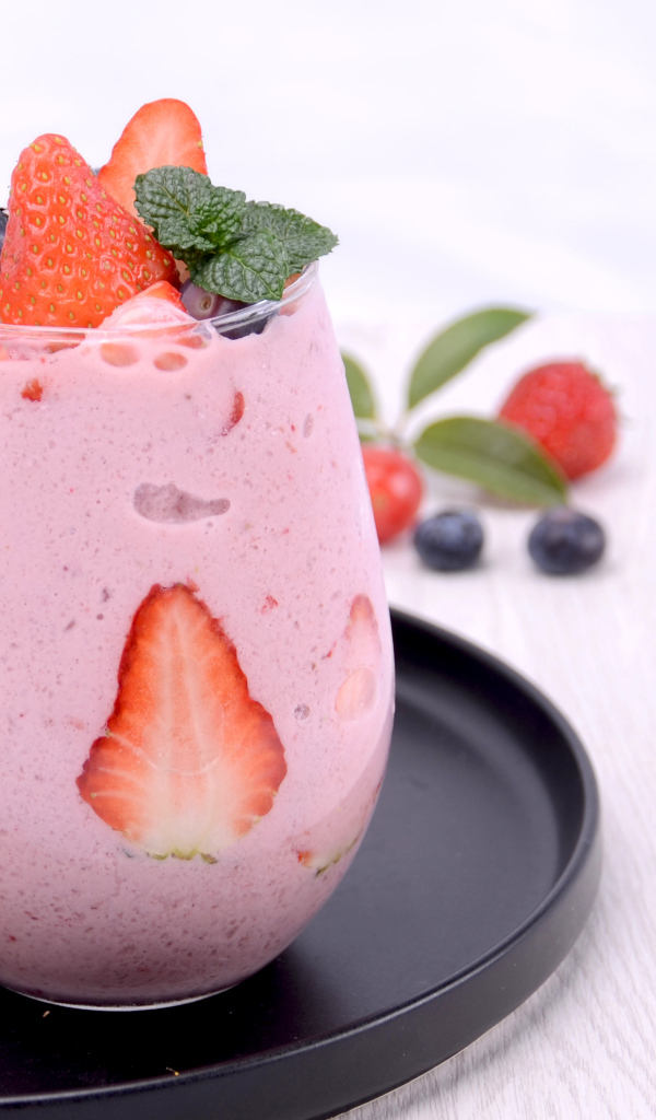 Йогурт в стакане с ягодами черники и клубники