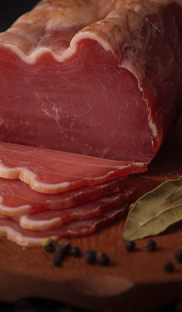 Кусок вяленого мяса на доске с черным хлебом и специями