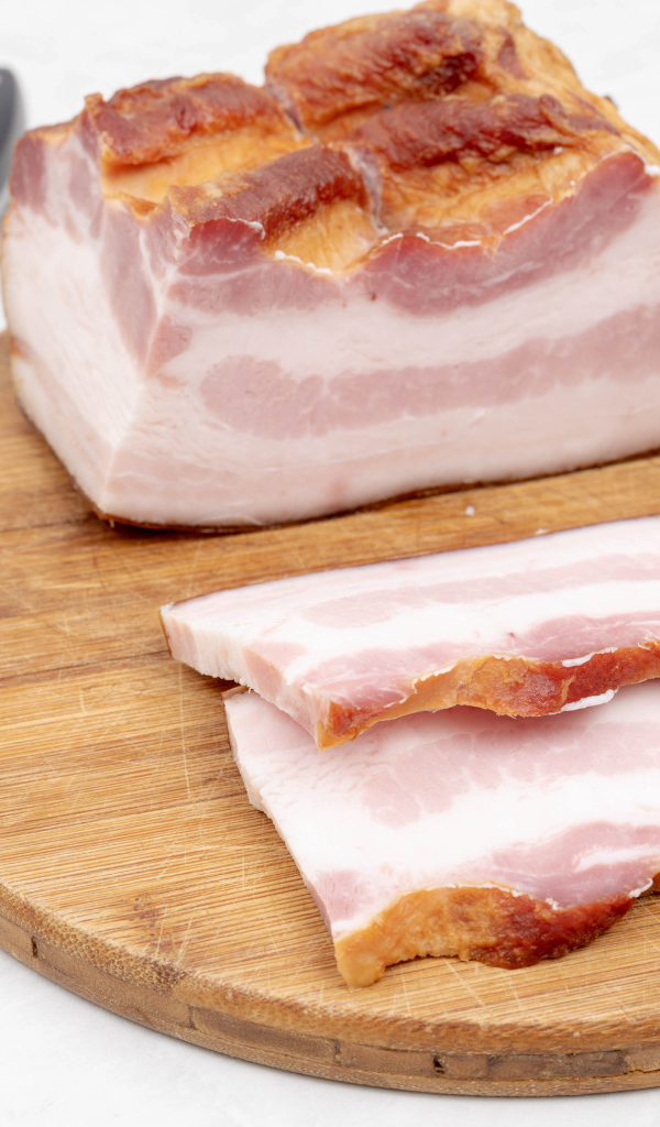 Кусок вкусного копченого сала на доске с ножом