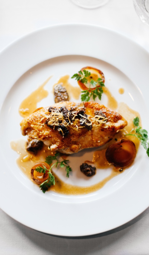 Кусок жареного мяса на большой белой тарелке 