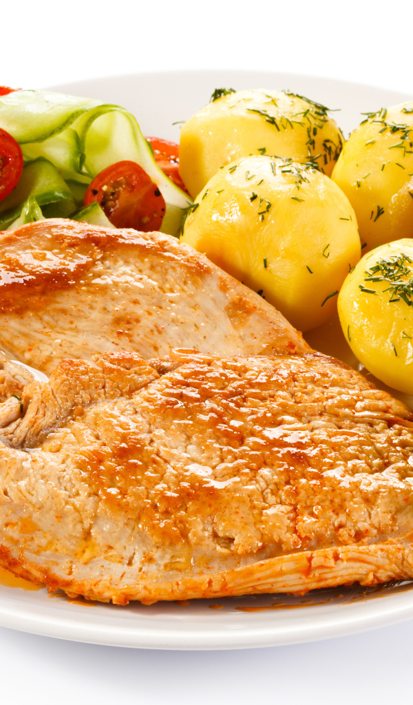 Кусок сочного куриного мяса на тарелке с картофелем и салатом