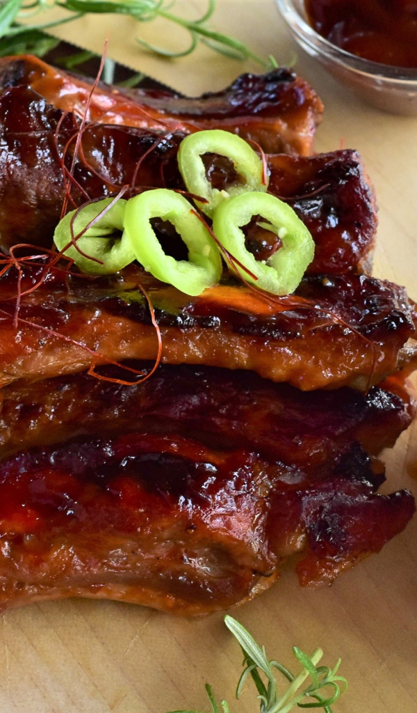 Аппетитные жареные ребрышки на столе с огурцами  и соусом 