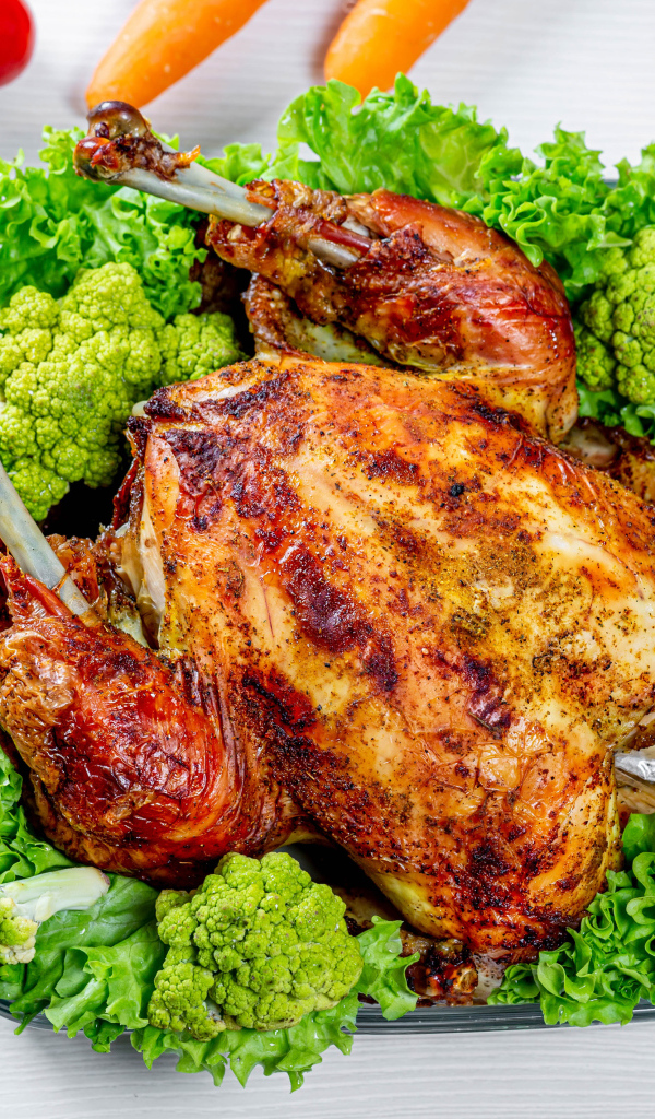 Запеченная курица с брокколи и листьями салата на столе с овощами