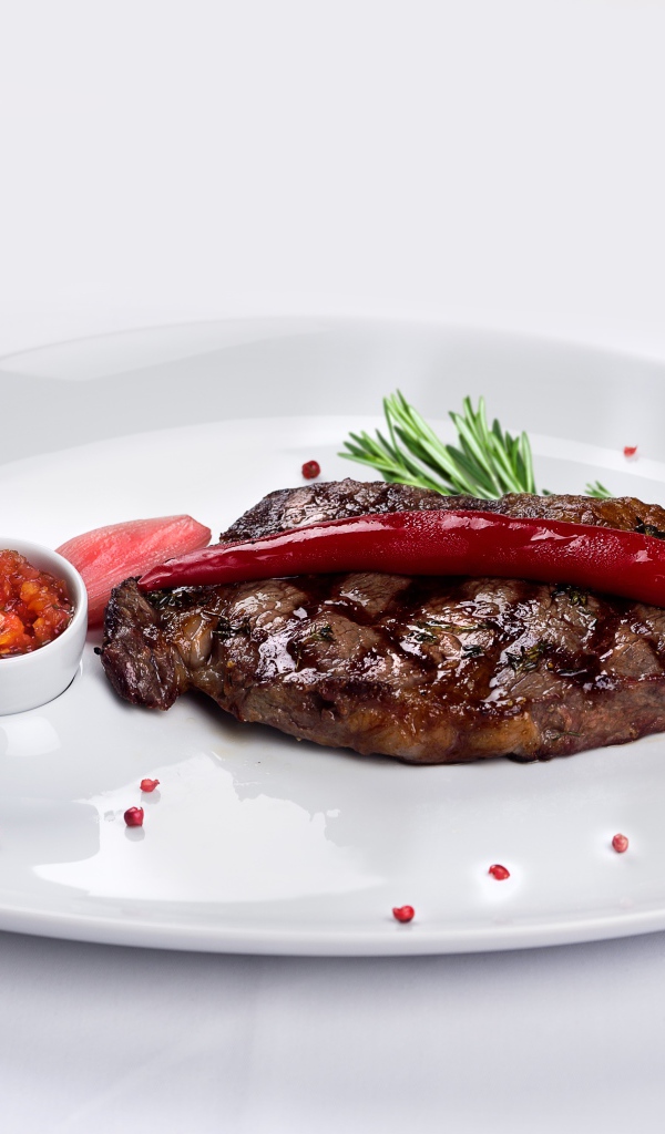 Стейк с кровью на тарелке с красным перцем