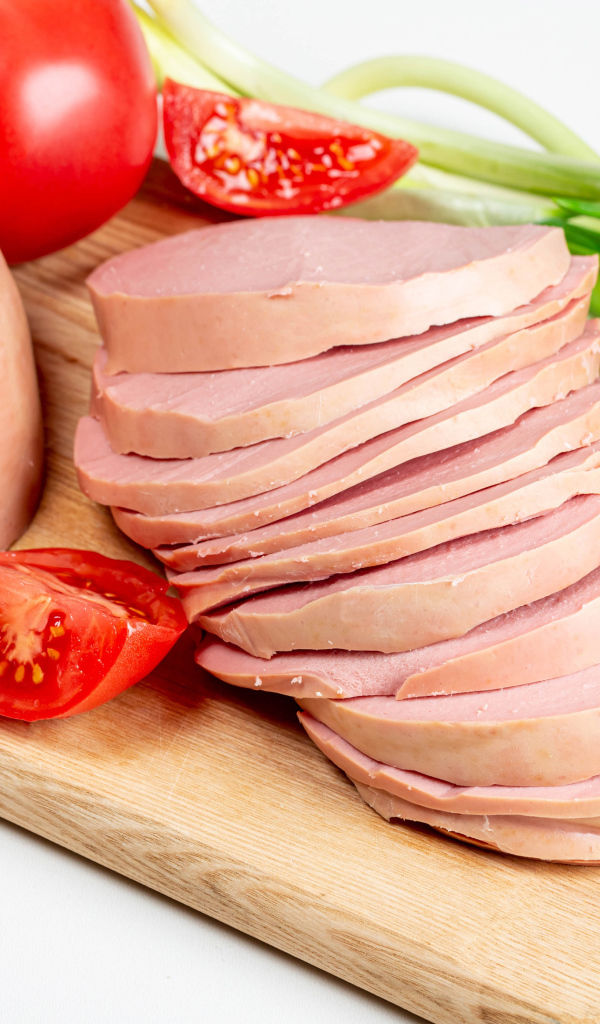 Вареная колбаса на доске с луком и помидором