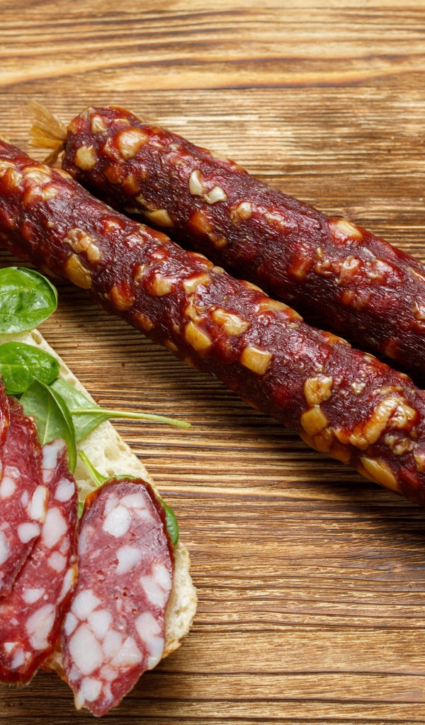 Вкусная сухая колбаса на столе с бутербродом