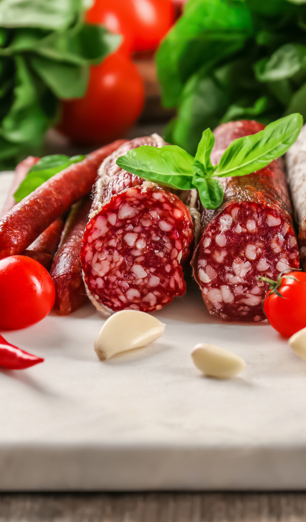 Вкусные колбасные изделия на столе с овощами