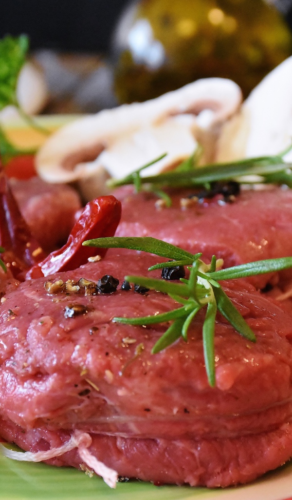 Свежее мясо маринуется со специями на столе с грибами