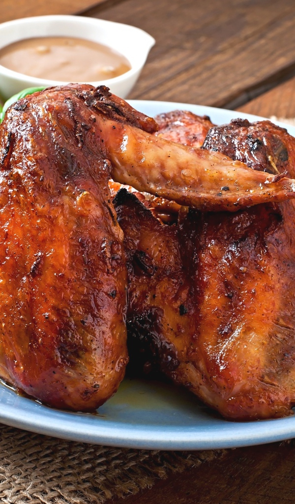 Зажареные куриные крылышки на столе с соусом и базиликом