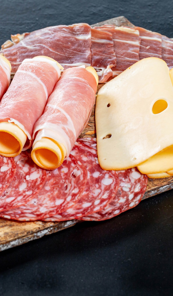 Рулеты из ветчины с сыром на столе с колбасой и мясом