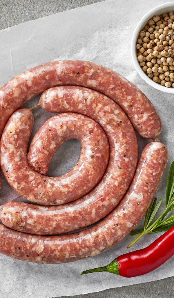 Домашняя колбаса на столе с зеленью и перцем