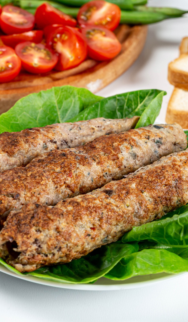Мясное блюдо кебаб на столе с зелеными листьями 