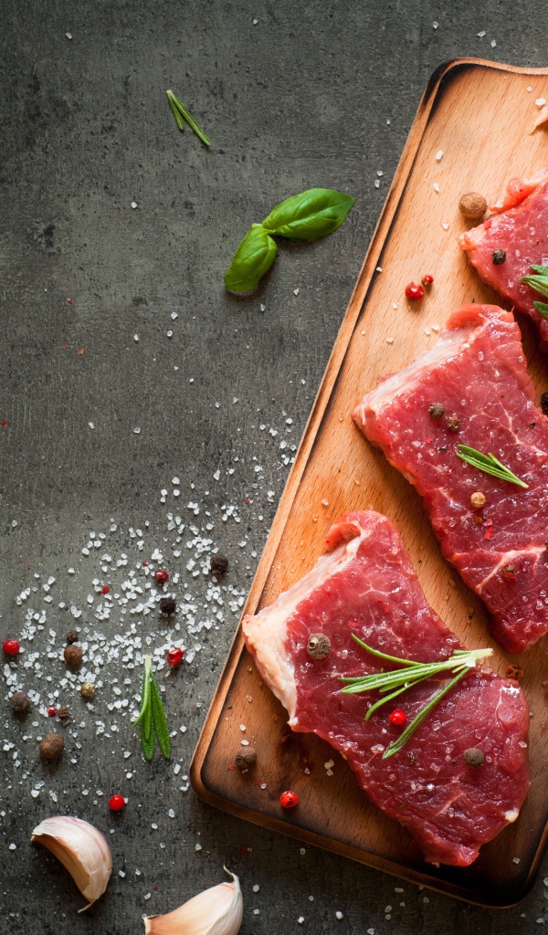 Куски мяса со специями и зеленью на доске 