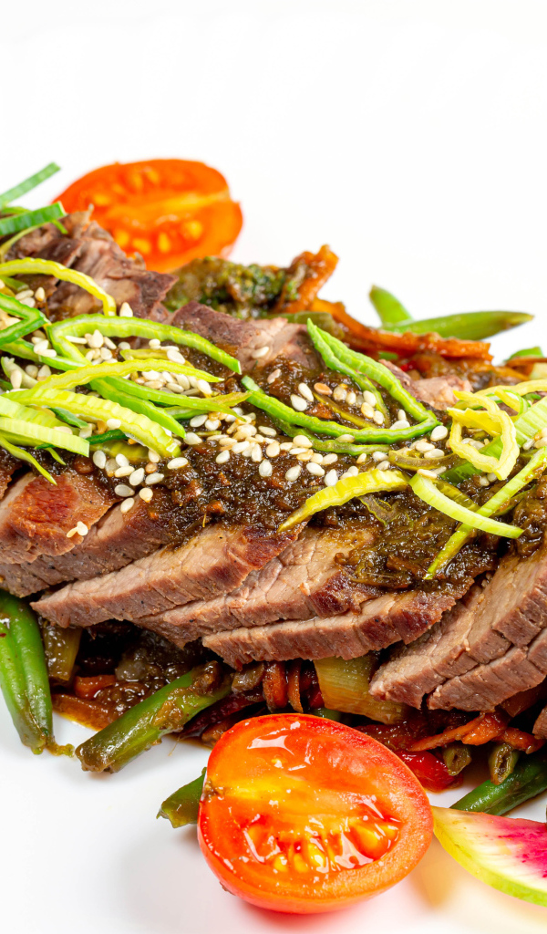 Мясо нарезанное кусочками на белом фоне с овощами