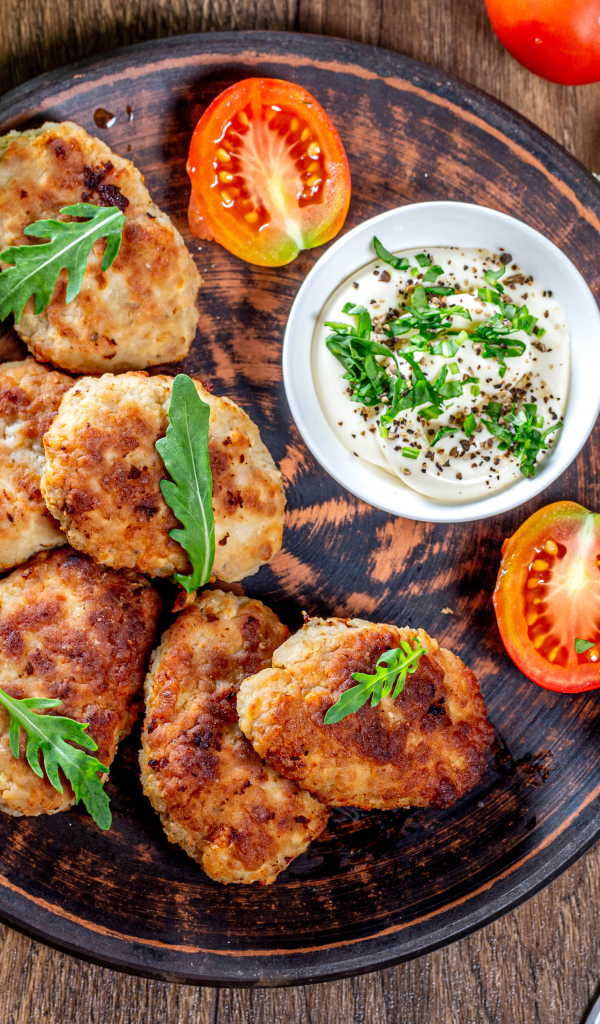 Вкусные котлеты на столе с соусом и помидорами