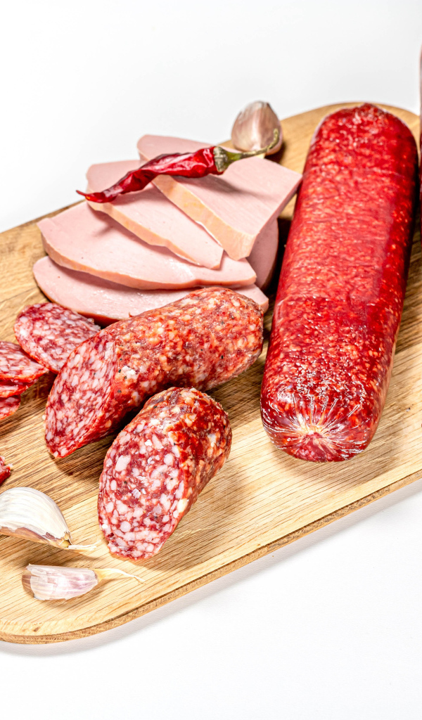 Вкусная колбаса с красным перцем и чесноком на доске на белом фоне