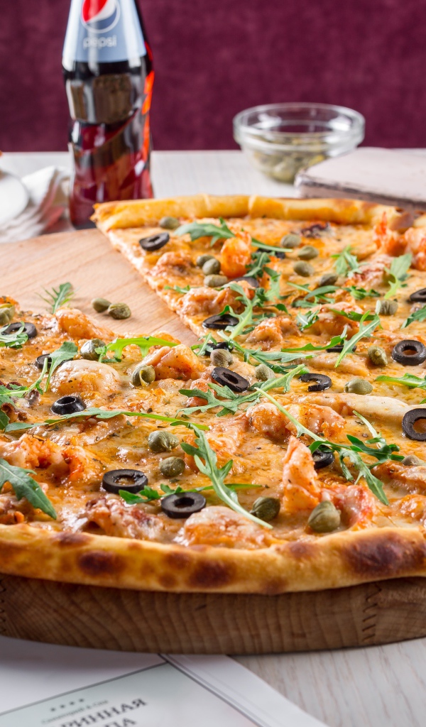 Большая аппетитная пицца с маслинами на столе в кафе