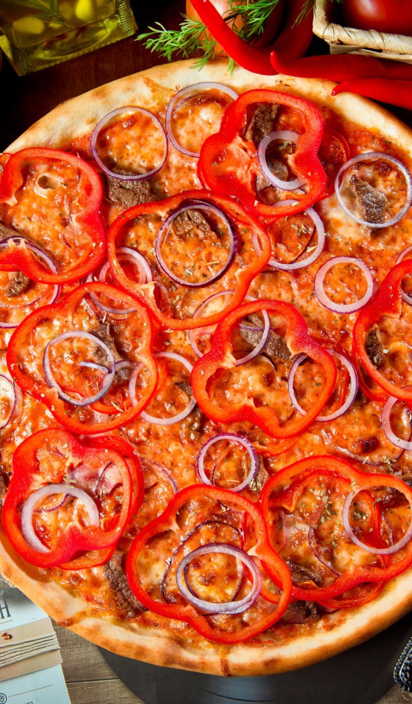 Большая пицца с мясом, луком и болгарским перцем на столе 