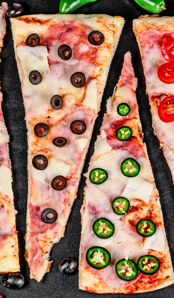 Четыре куска аппетитной пиццы с ветчиной и острым перцем