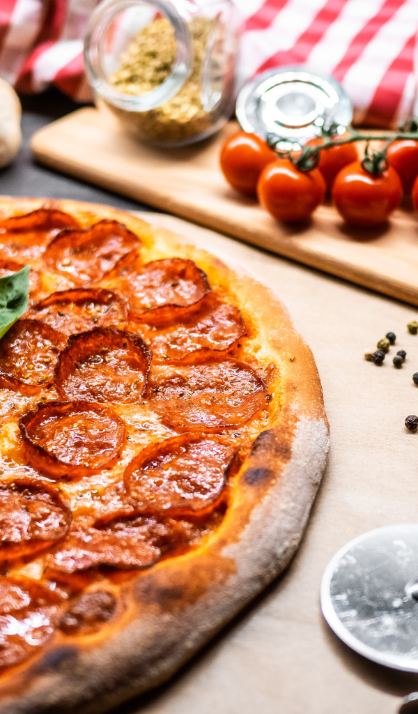 Пицца пепперони на столе с овощами и специями